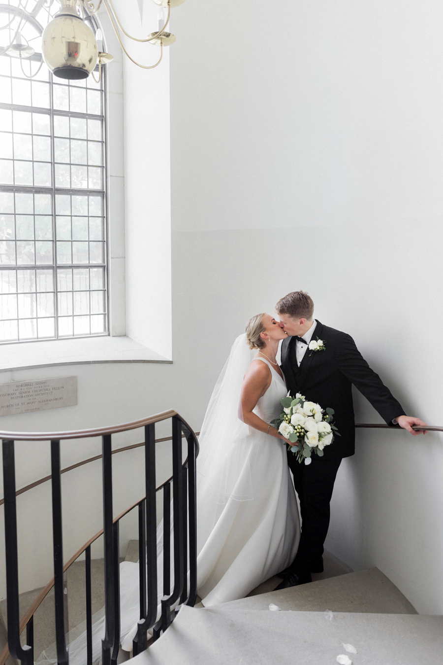 The bride and groom pose for portraits in the circular staircase at the Church of St. Mary, Aldermanbury at a Westminster College wedding by Love Tree Studios.