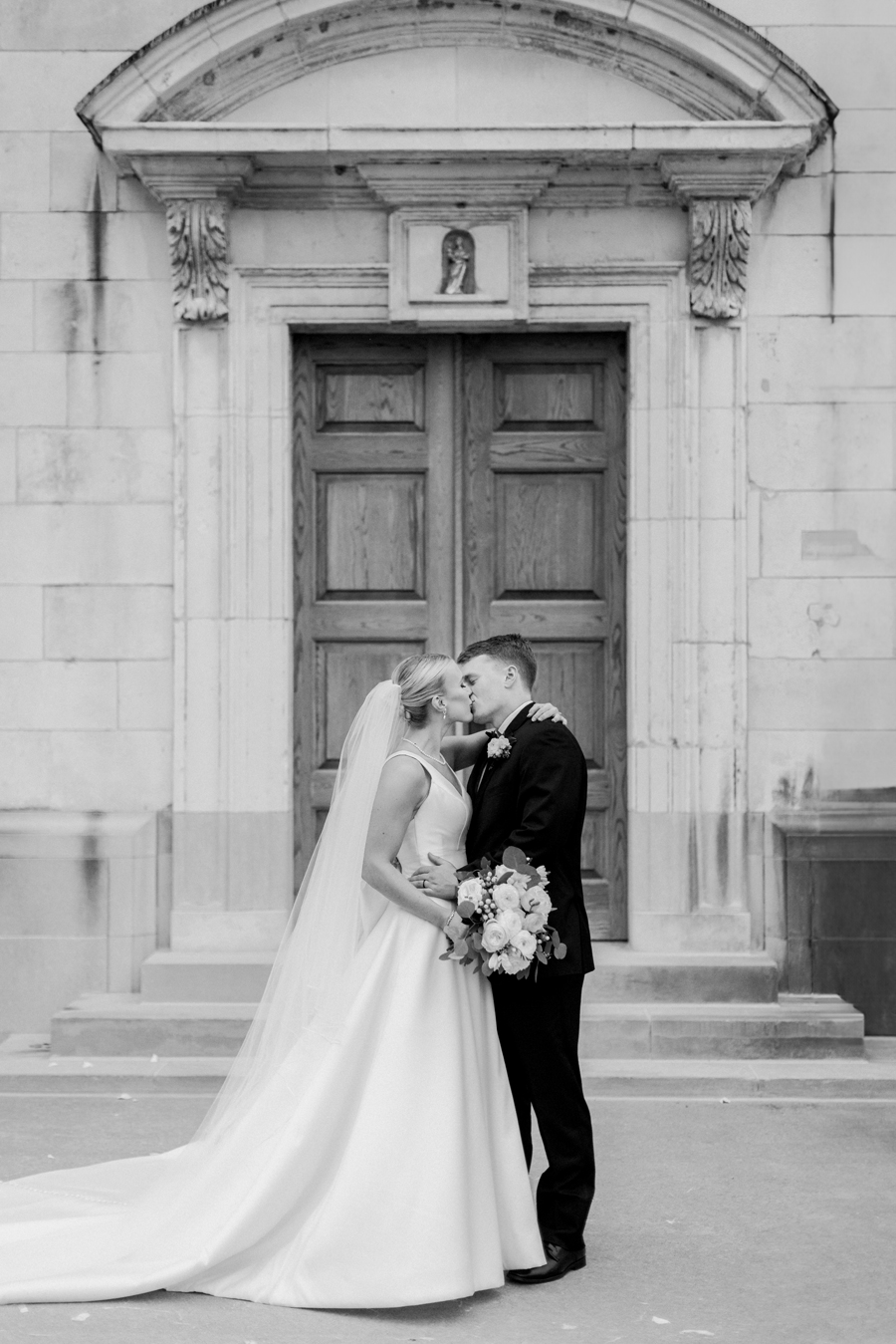 A bride and groom take portrait outside the Church of St. Mary, Aldermanbury at a Westminster College wedding by Love Tree Studios.