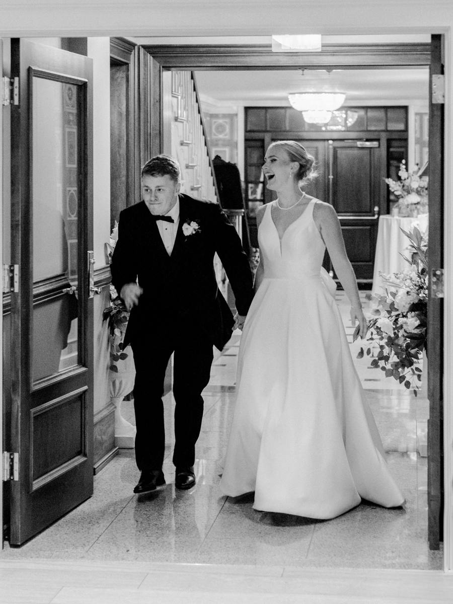 A bride and groom enter their reception at the Club at Old Hawthorne for a Westminster College wedding by Love Tree Studios.
