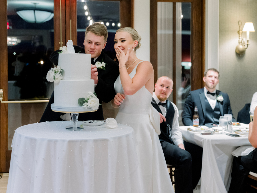 A bride and groom cut the cake at the Club at Old Hawthorne for a Westminster College wedding by Love Tree Studios.