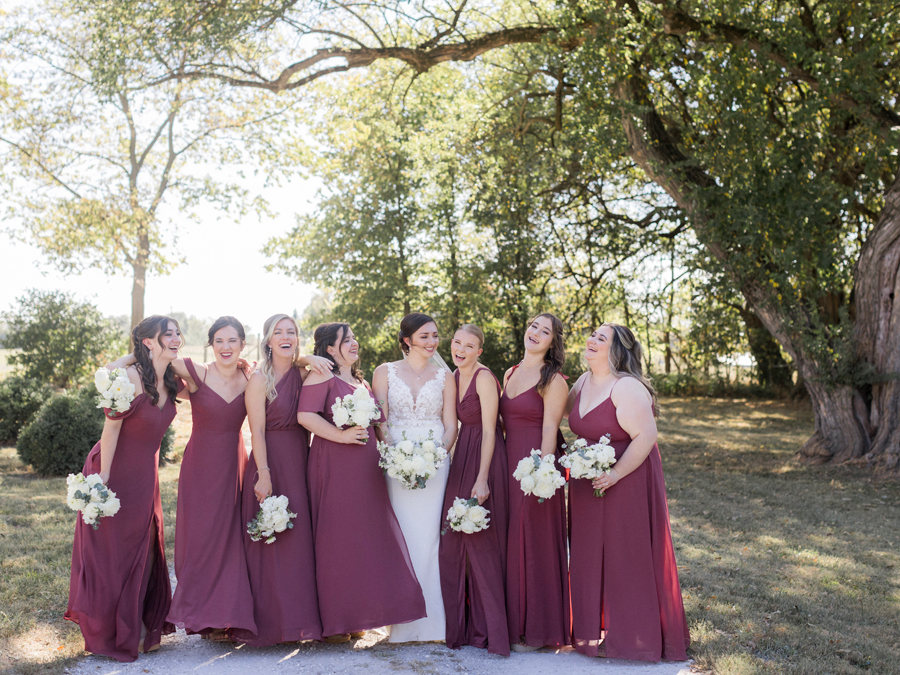 A bride poses with her bridesmaids for her Blue Bell Farm wedding by Missouri wedding photographer Love Tree Studios.