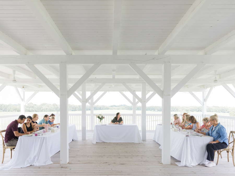 A wide shot of Blue Bell Farm’s porch, filled with attendees savoring the breeze, birdsong, and views during the paint and picnic event.