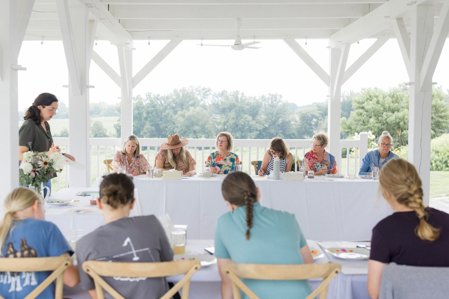 Attendees seated at a table, painting under the guidance of Caitlin Allen Studios during the paint and picnic event.