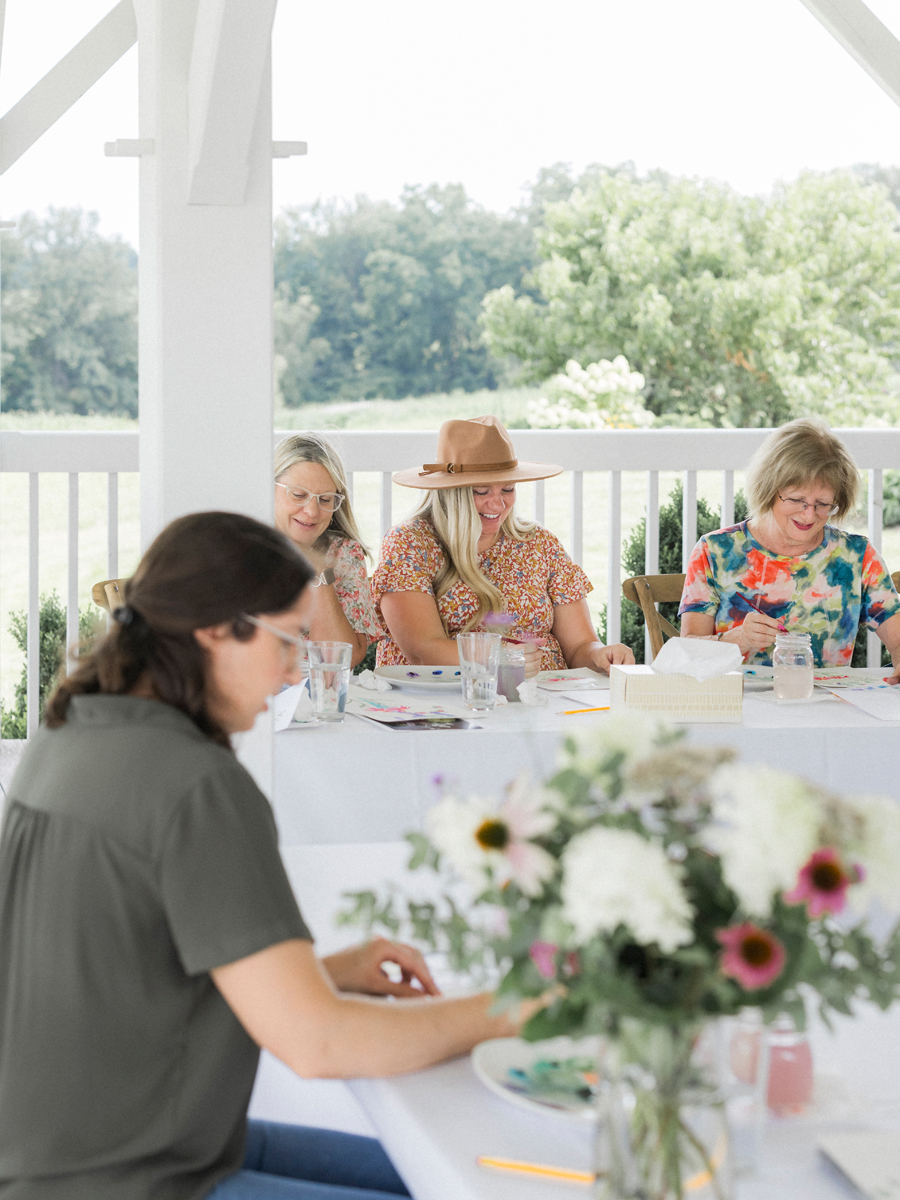 Attendees seated at a table, painting under the guidance of Caitlin Allen Studios during the paint and picnic event.