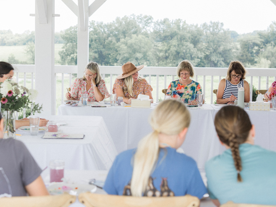 Attendees seated at a table, painting under the guidance of Caitlin Allen Studios during the paint and picnic event.