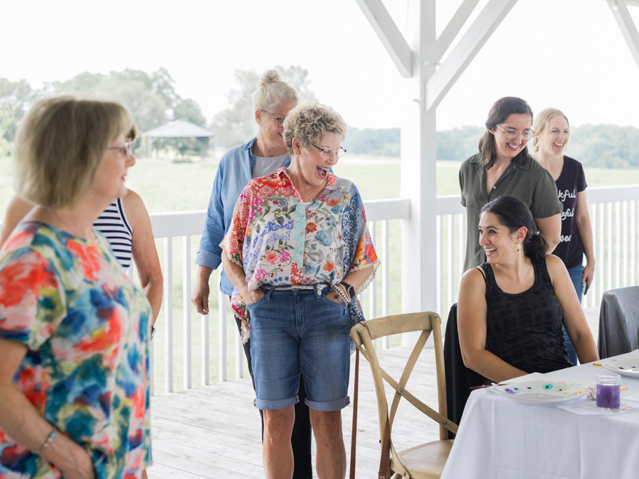 Friends laughing and encouraging each other’s artwork, capturing the camaraderie at the paint and picnic event.