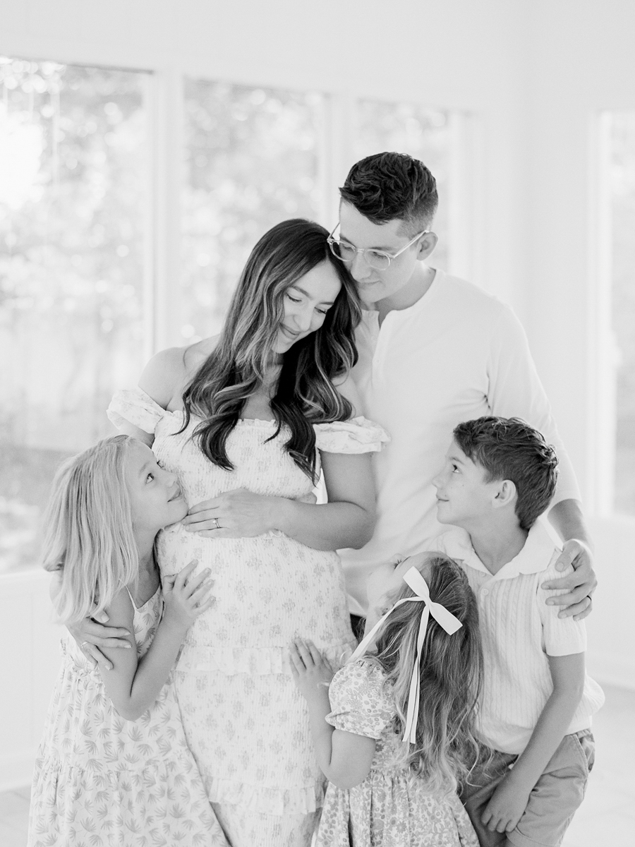 The Bedford family standing together in the Garden Studio in Columbia, Missouri, celebrating their upcoming addition during a family maternity session by Love Tree Studios.