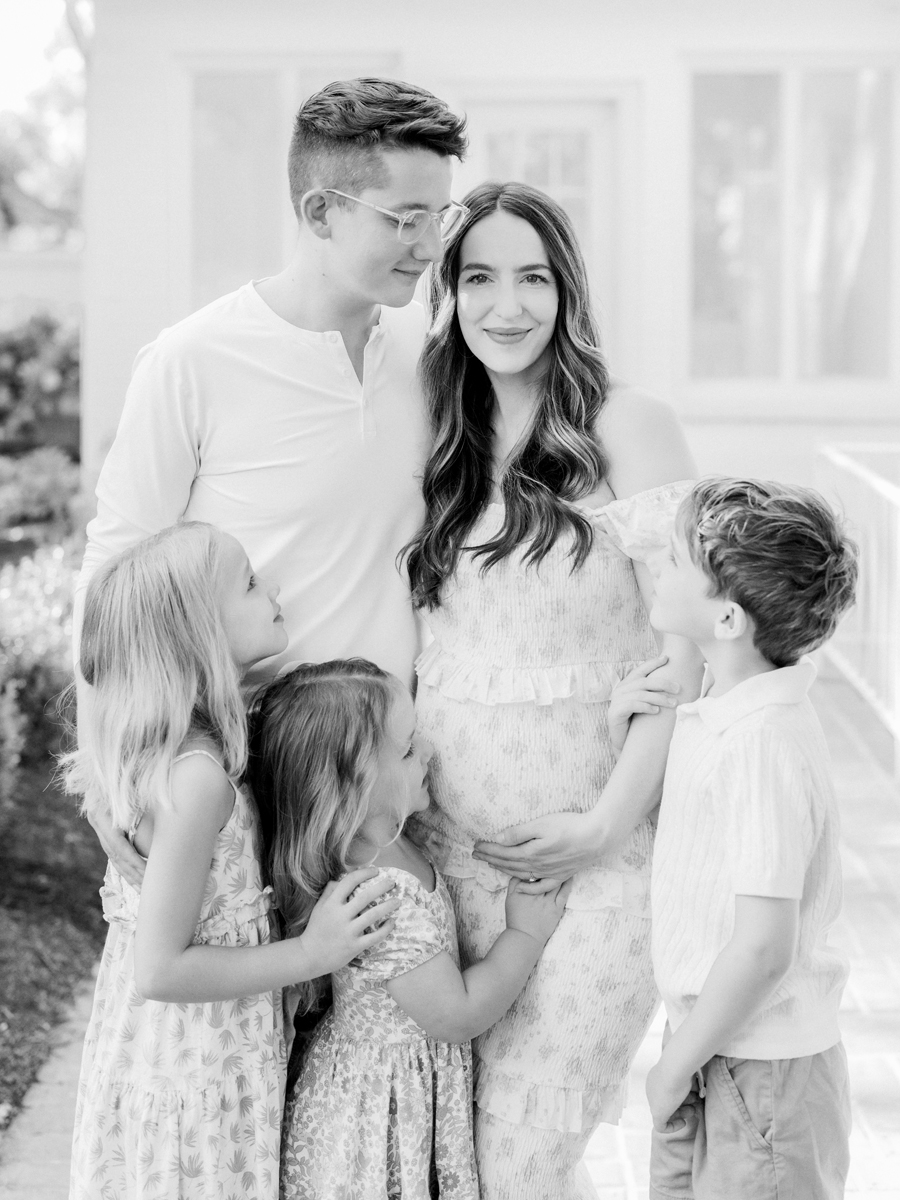 The Bedford family standing together in Love Tree Studio's Garden Studio in Columbia, Missouri, celebrating their upcoming addition during a family maternity session.