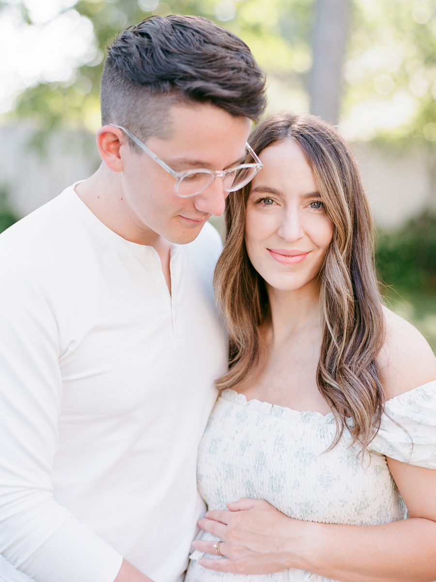 Mom and dad embracing with joy during their family maternity session in Love Tree Studio's outdoor Garden Studio in Columbia, Missouri.