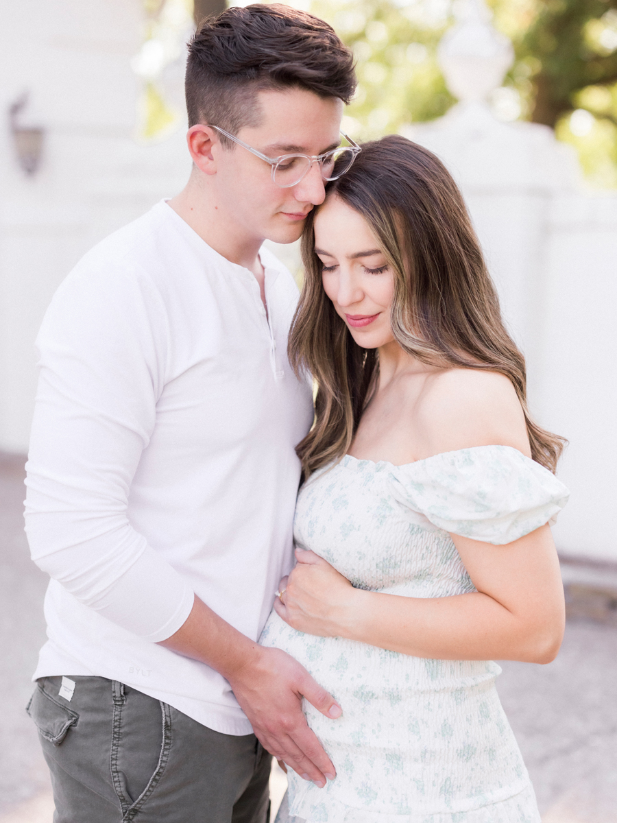 Parents sharing a joyful embrace in their Columbia, Missouri, family maternity session, surrounded by soft sunlight at Love Tree Studio's Garden Studio.