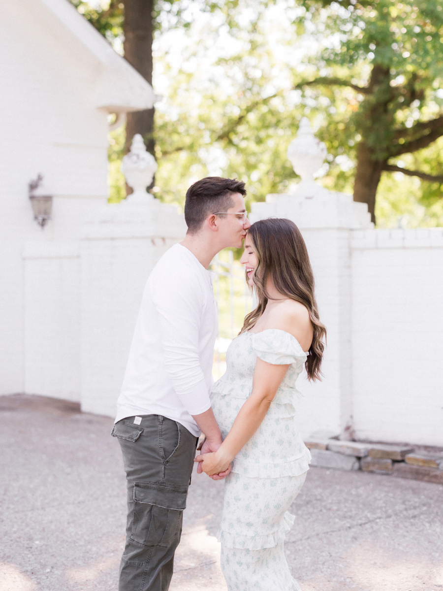 A father kisses the mother on the forehead while smiling in Columbia, Missouri, during a family maternity session by Love Tree Studios.