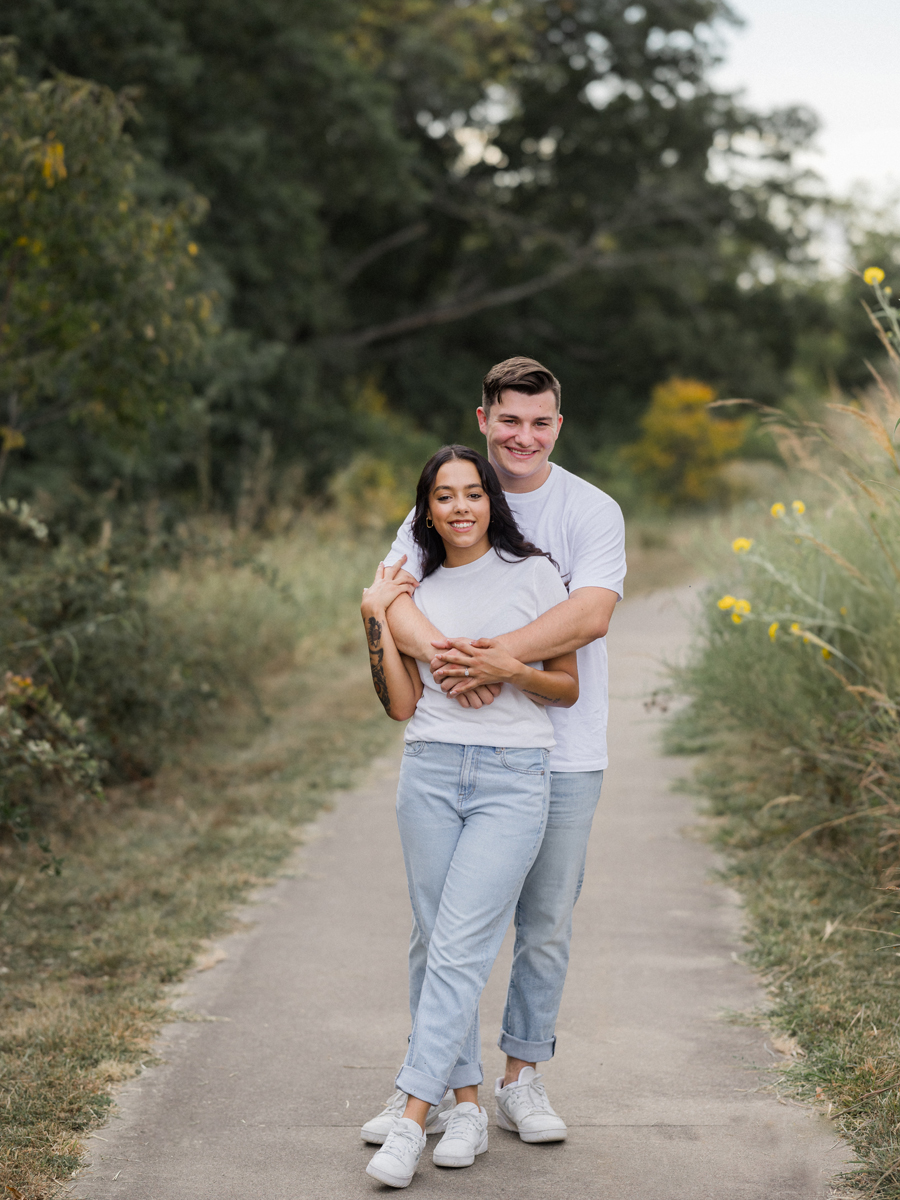 Engaged couple standing in front of tall trees in Columbia, Missouri.