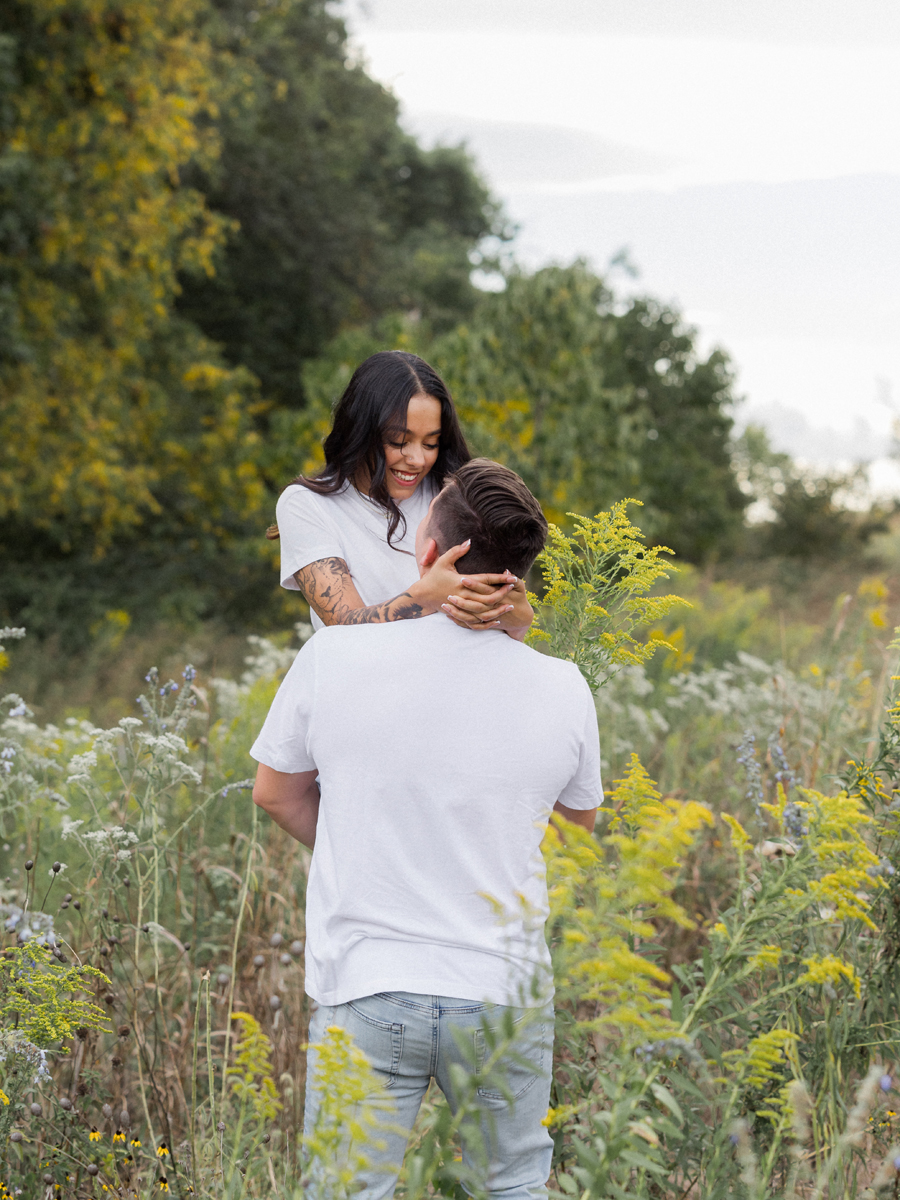 Bryanna and Chase holding hands and laughing in a Missouri field.