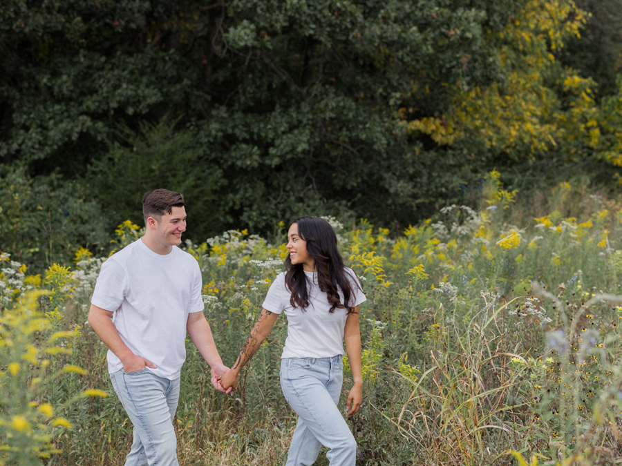 Engaged couple walking through a grassy field in Columbia, Missouri.