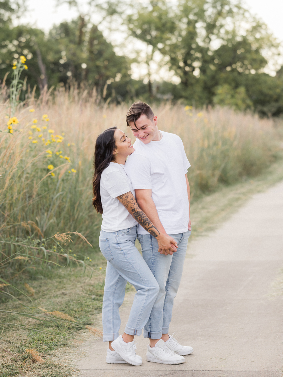 Couple standing together in matching white t-shirts and sneakers during their engagement session.