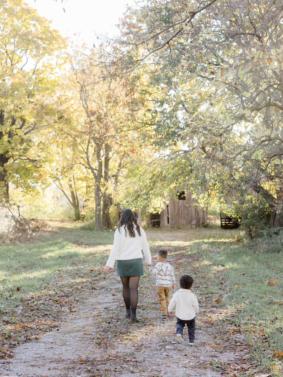 The Washington family walk near a rustic barn at Pierpont Farms Family Session, photographed by Love Tree Studios.