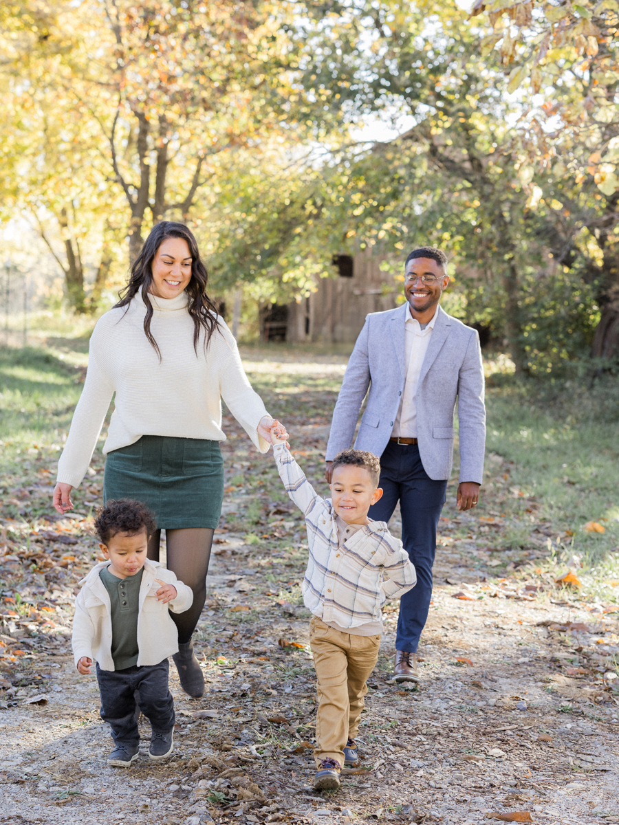 The Washington family walking hand-in-hand along a rustic path at Pierpont Farms Family Session, captured by Love Tree Studios.