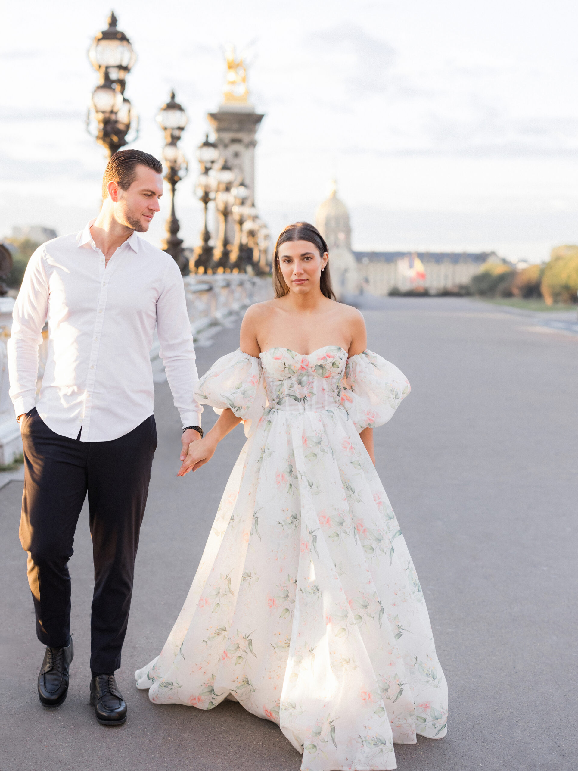 Sinaï and Abraham standing on Pont Alexandre III Bridge at sunrise, embracing in golden light during their Paris portrait session by Love Tree Studios.