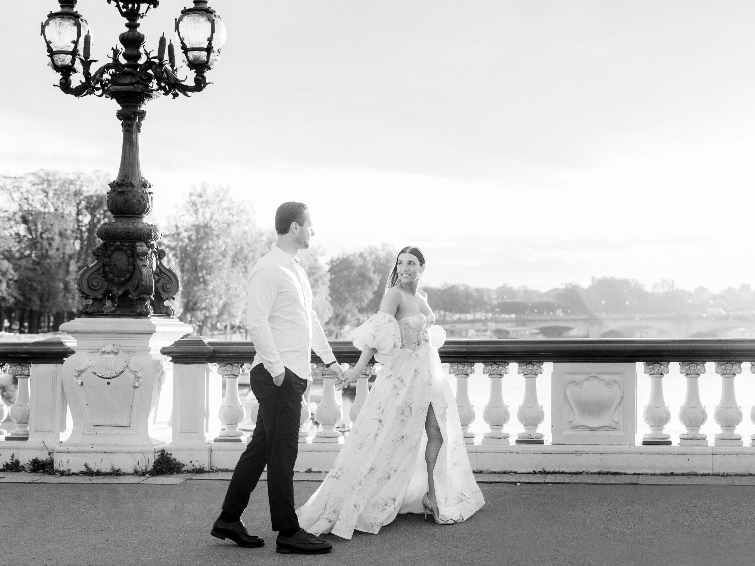 Sinaï and Abraham’s silhouettes framed by the ornate bridge railings and lampposts during their Paris portrait session Love Tree Studios.