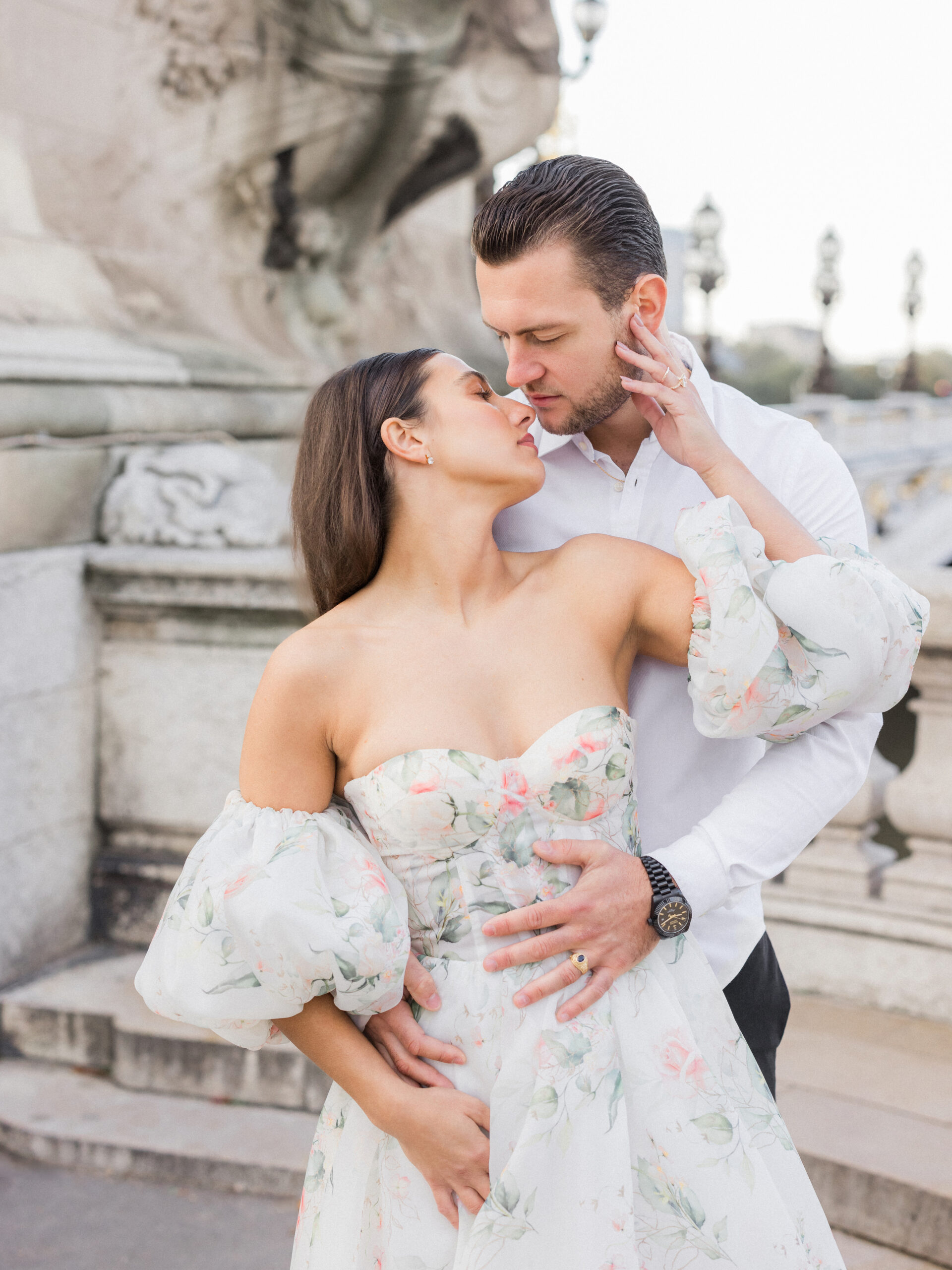 Sinaï adjusting Abraham’s collar as they laugh together in the warm morning light during their Paris portrait session.