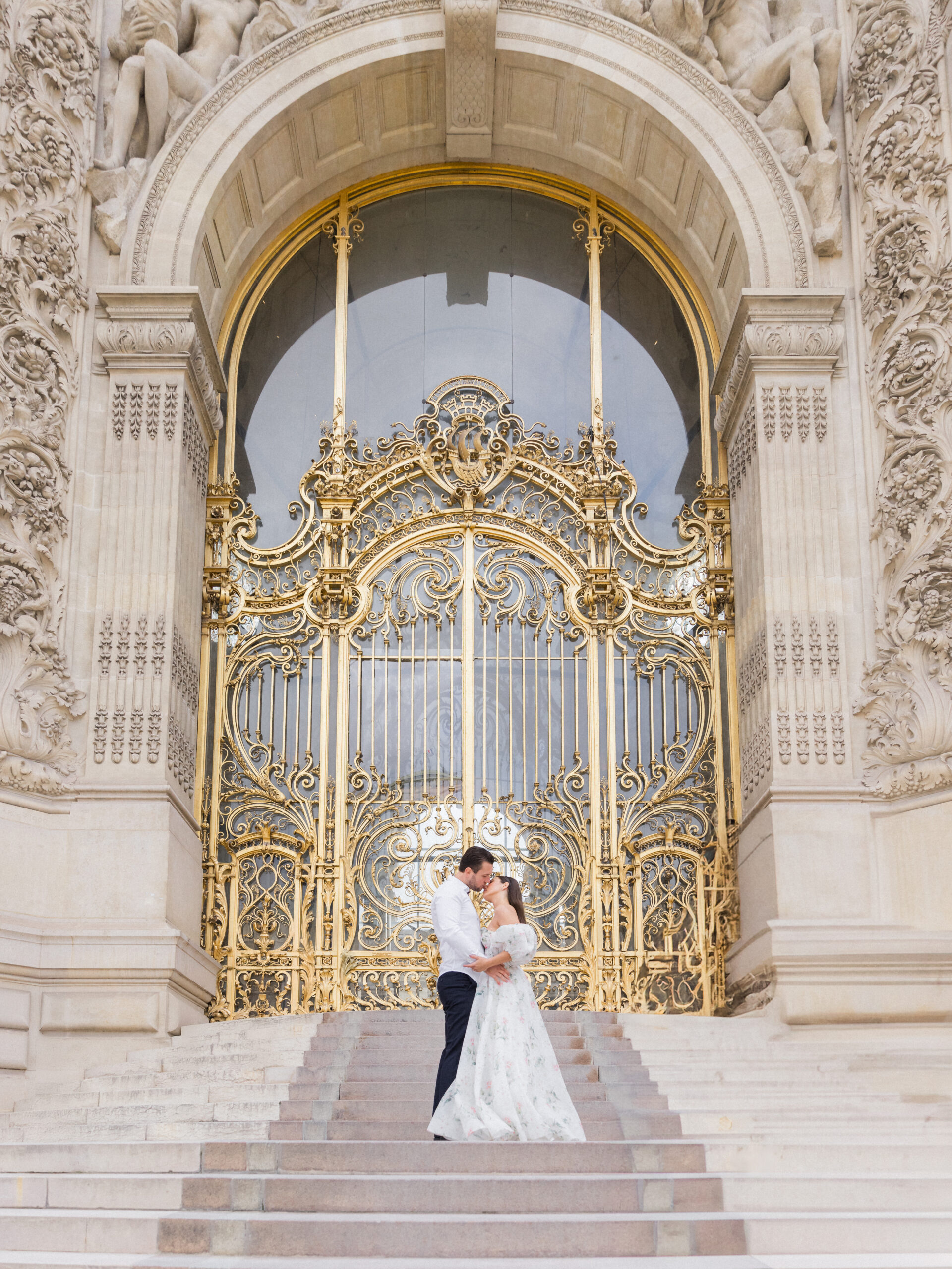 Sinaï and Abraham kiss in front of the grand golden gate at La Petite Palace.