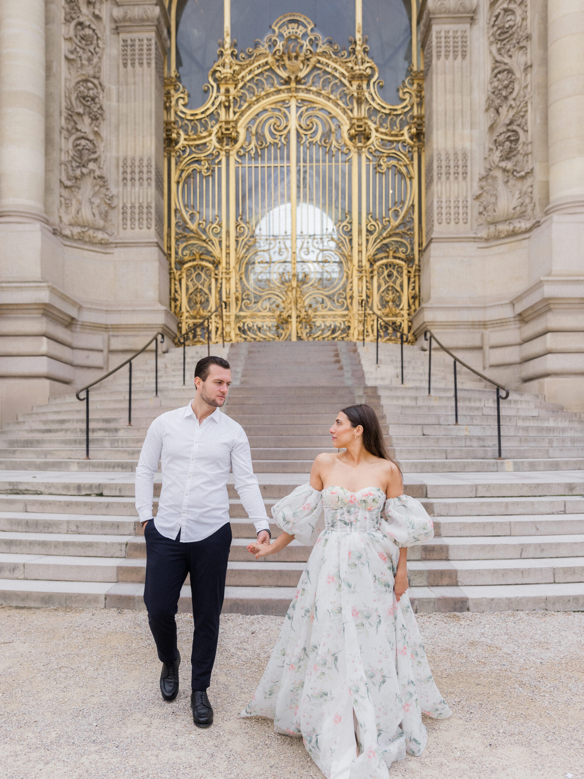 Sinaï and Abraham walking down the steps of the grand golden gate at La Petite Palace Love Tree Studios.