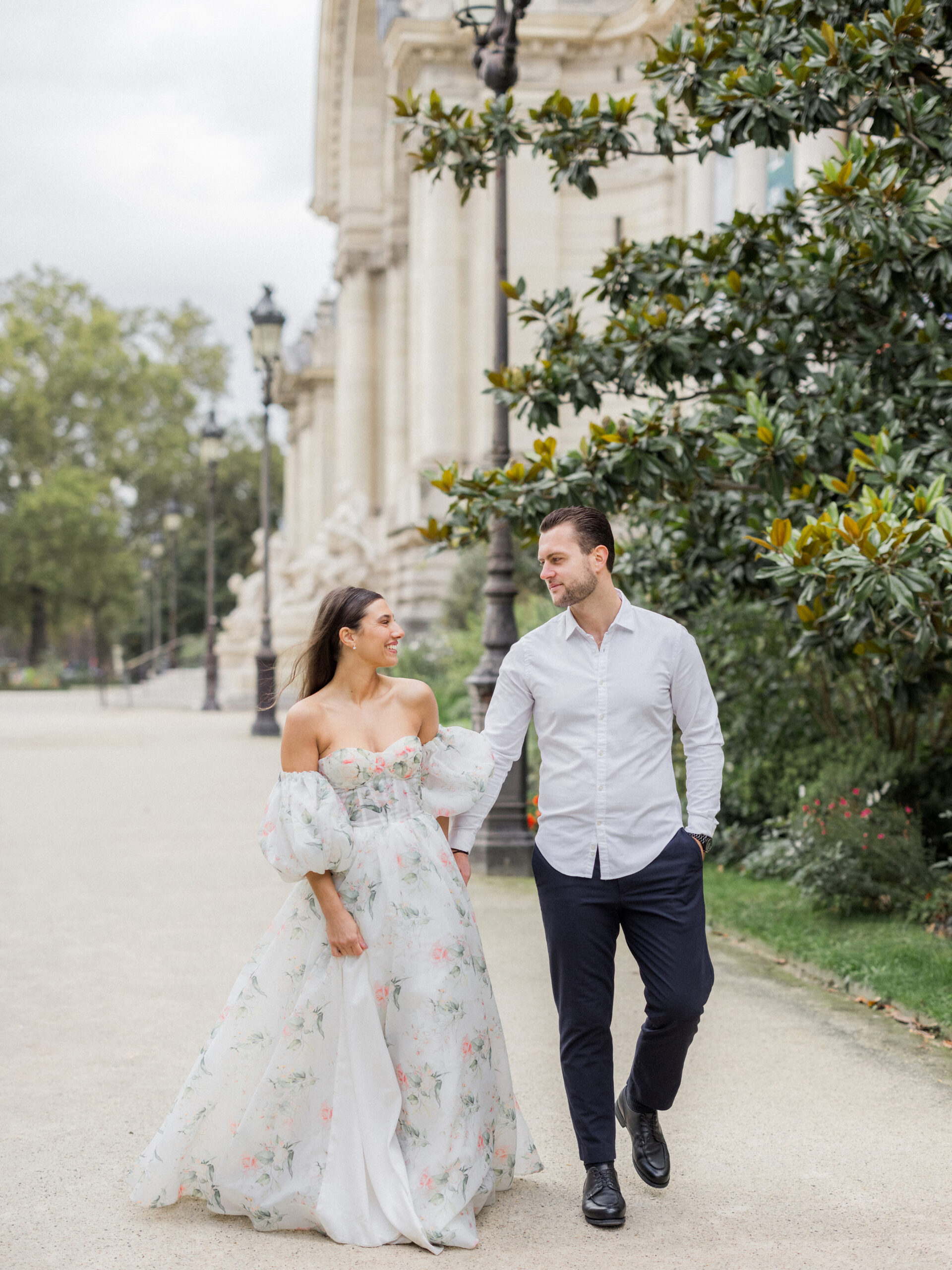 Romantic portrait of Sinaï and Abraham smiling near the elegant architecture of La Petite Palace.