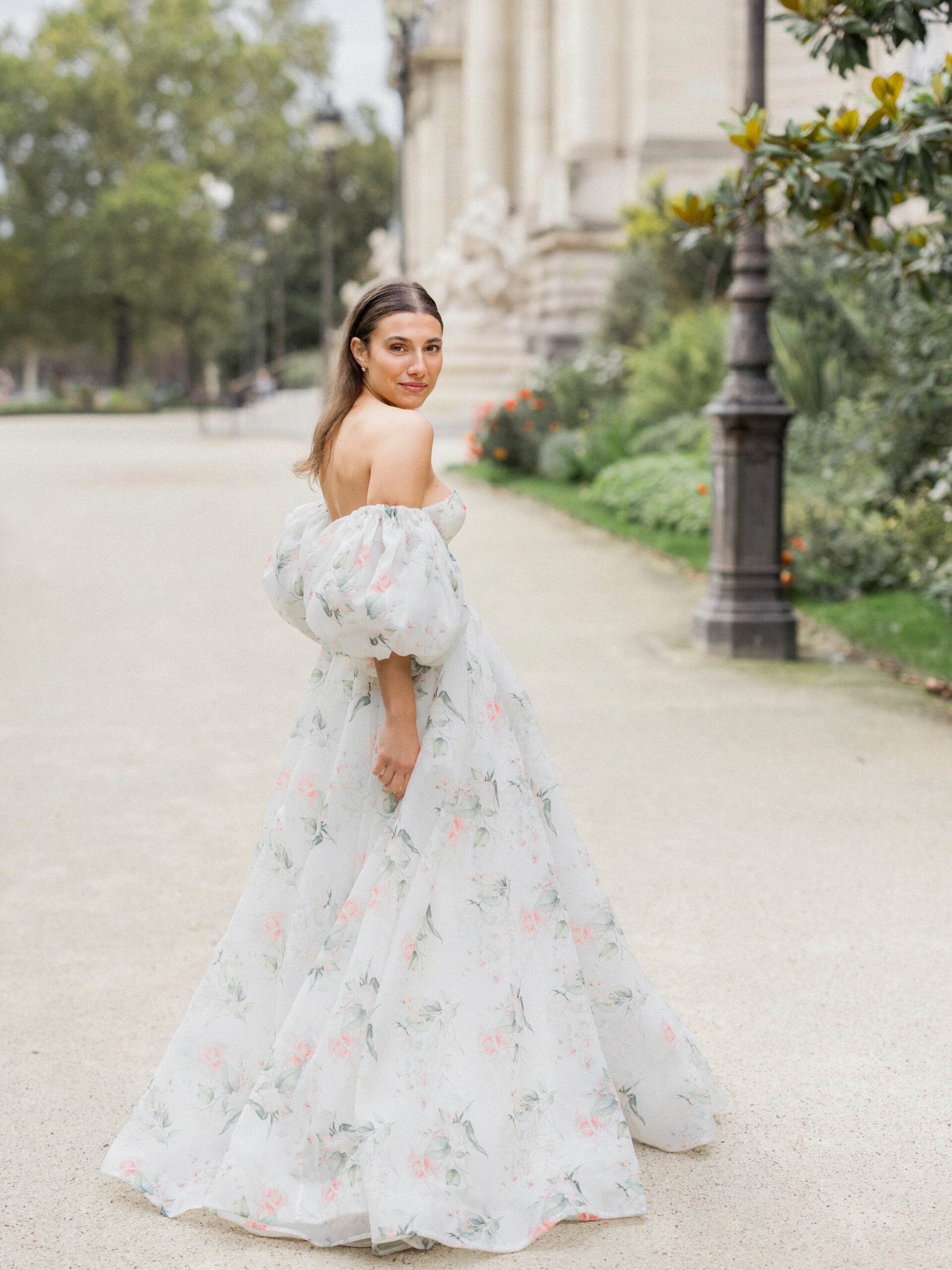 Wide-angle shot of Sinaï in her floral gown, with La Petite Palace’s beautiful facade in the background.