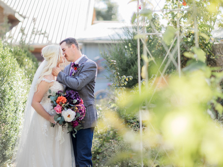 Couple sharing a romantic moment in front of the rustic barn at their chic Western Missouri wedding by Love Tree Studios.