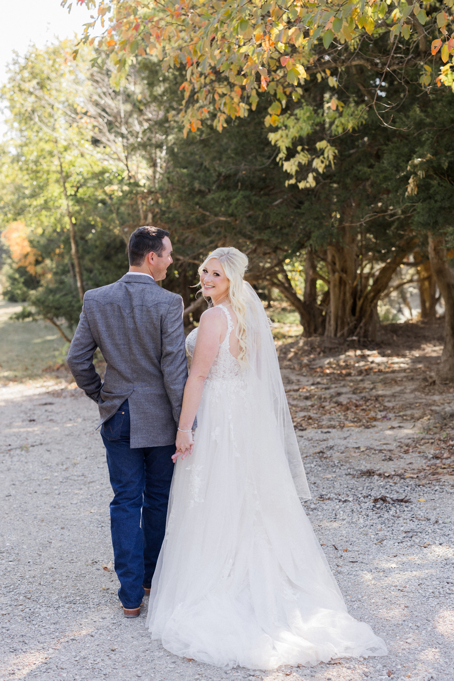 Bride and groom walking hand-in-hand at their chic Western Missouri wedding, photographed at Alpine Park and Gardens by Love Tree Studios.