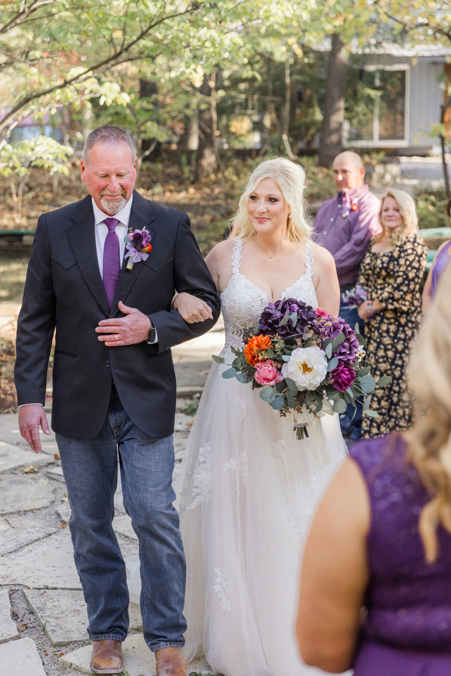 Bride walking down the aisle in cowboy boots during her chic Western Missouri wedding, photographed by Love Tree Studios.