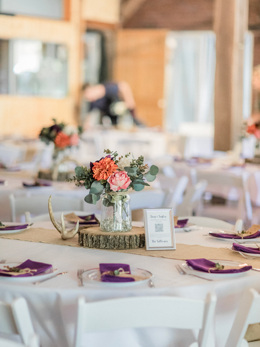 Rustic reception tables with vibrant floral arrangements at a chic Western Missouri wedding, photographed by Love Tree Studios.