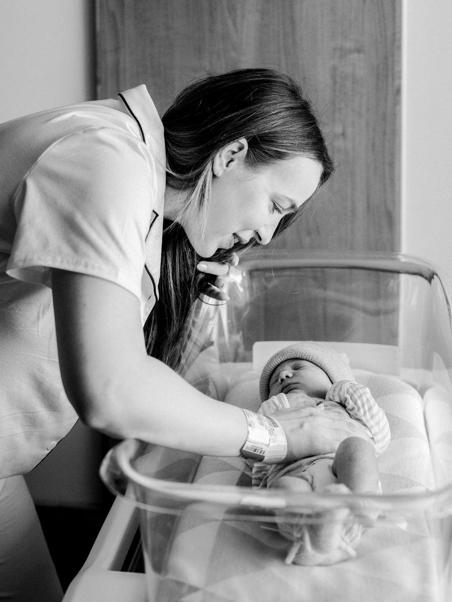 Black and white image of a newborn’s tiny hand grasping a finger—capturing pure love in a Fresh 48 session at Love Tree Studios.