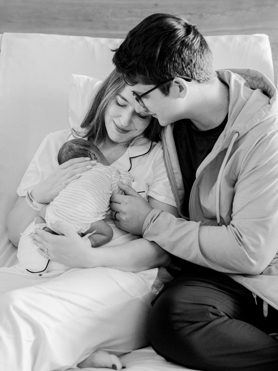 Fresh 48 photo of a newborn nestled in a parent’s arms, glowing with love and tenderness in black and white.