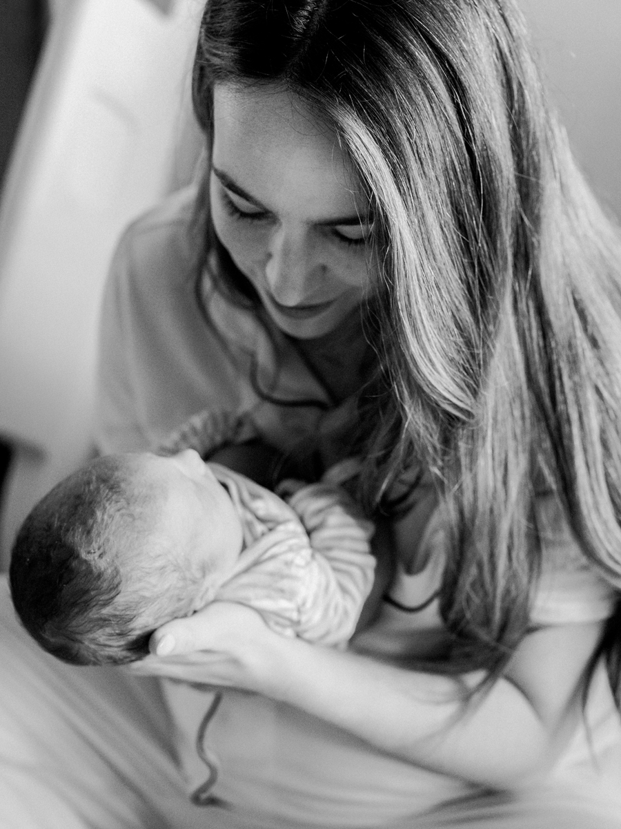 Image of a mother holding her newborn in a Fresh 48 session, captured beautifully in black and white.