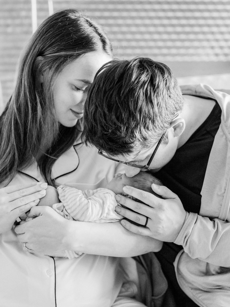 Black and white photo of parents admiring their newborn in a Fresh 48 session, filled with love and joy.