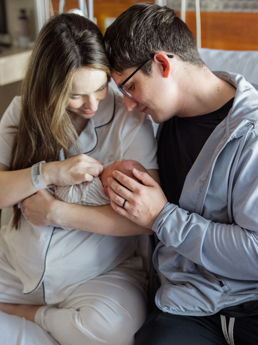 New parents lovingly gaze at their newborn in a Fresh 48 session photo, showcasing the joy of new life.