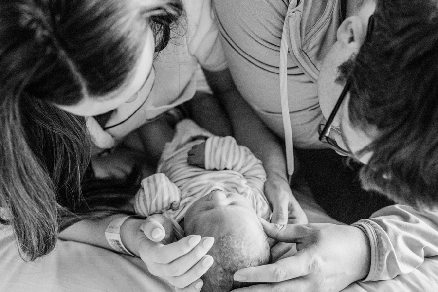 Stunning black and white photo of parents gazing at their newborn, celebrating the joy of a Fresh 48 session.