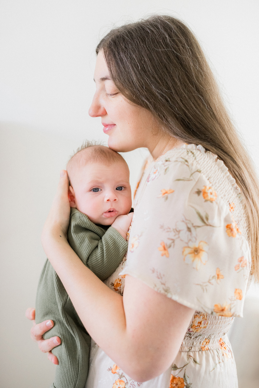 Mom cradling baby Corbin Wesley in a light-filled living room during a Columbia newborn photography shoot.