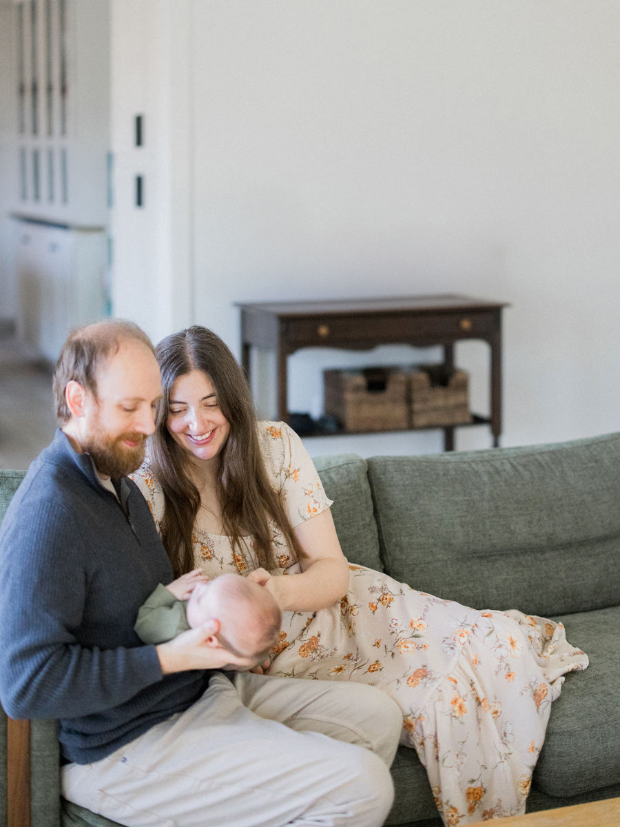 Family snuggles on the couch with baby Corbin Wesley in an in-home session by Love Tree Studios.