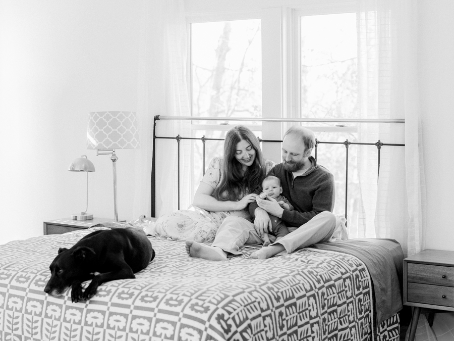 Family enjoying a relaxed moment in their bedroom during a Columbia newborn photography session by Love Tree Studios.