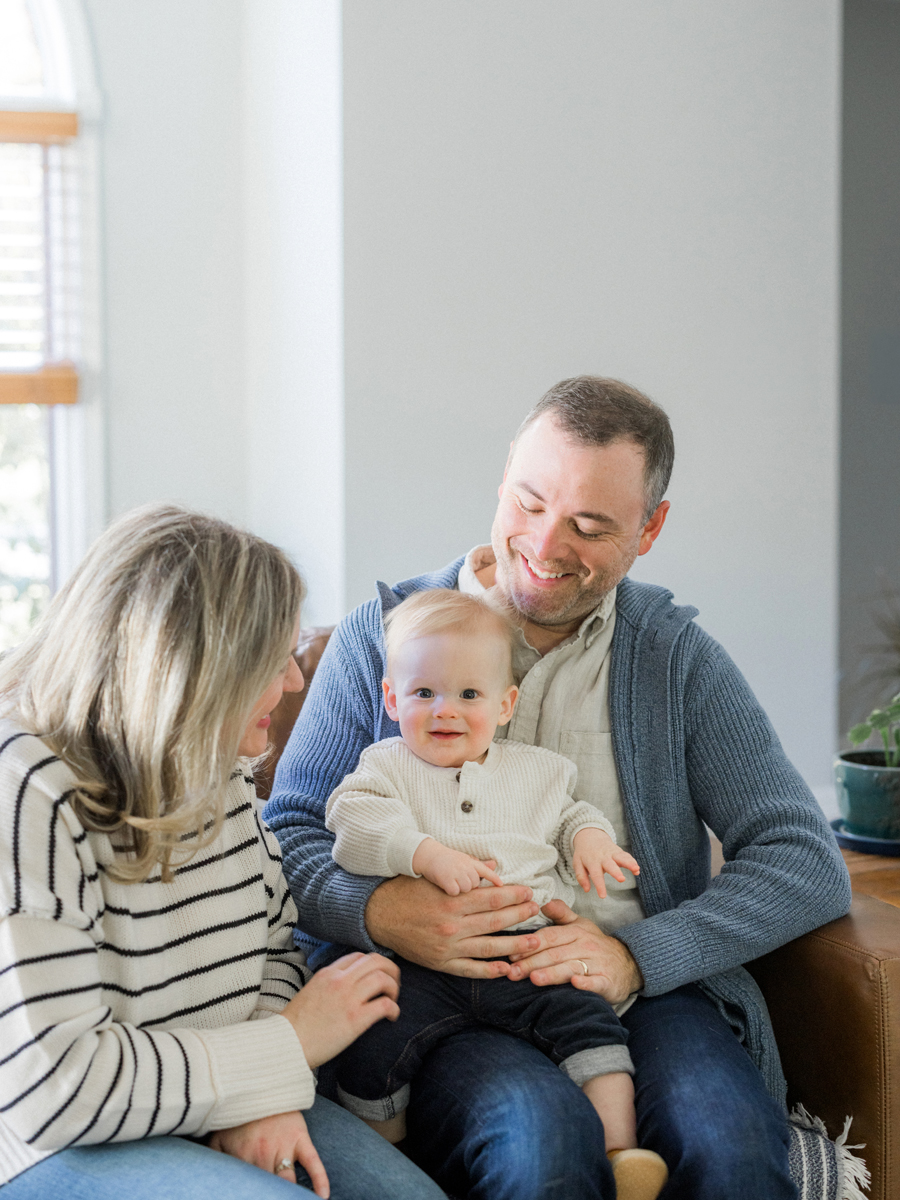 Parents laughing with their baby indoors, captured during a Love Tree Studios session in Columbia, MO.