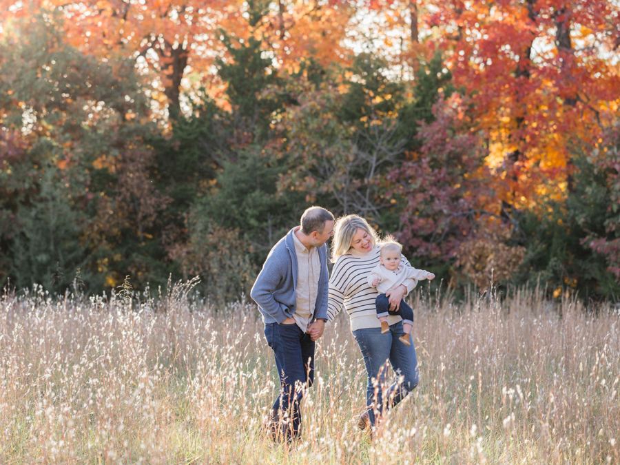 Baby Larsen being held by parents in an autumn field, captured by Love Tree Studios in Columbia, MO.