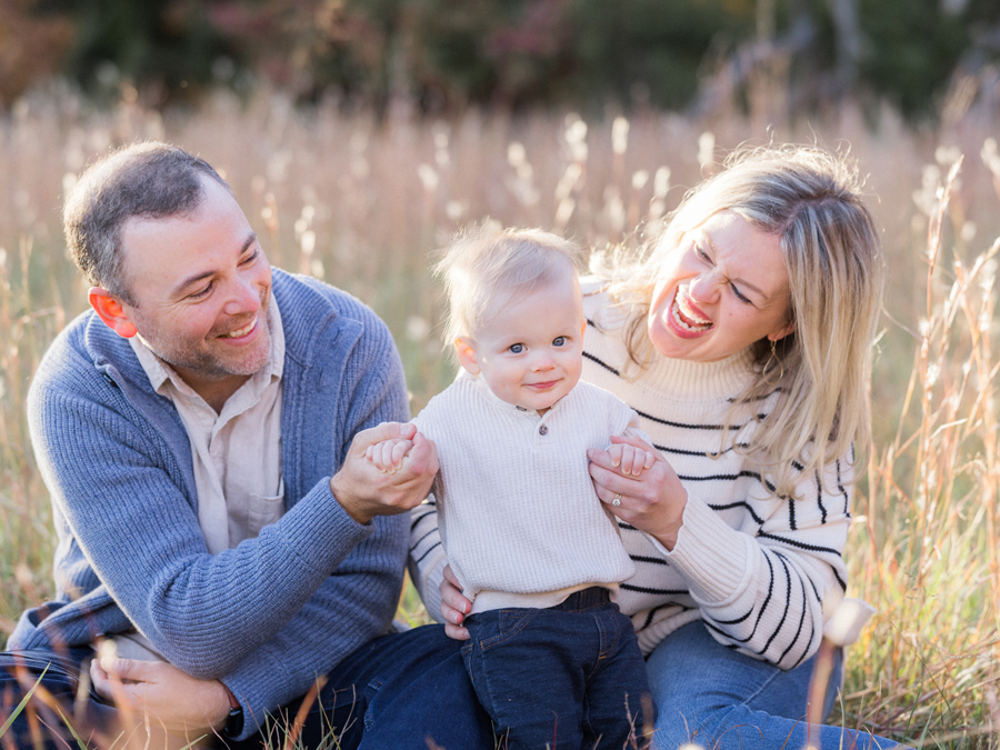 Candid moment of parents and baby laughing together outdoors, captured by Love Tree Studios in Columbia, MO.