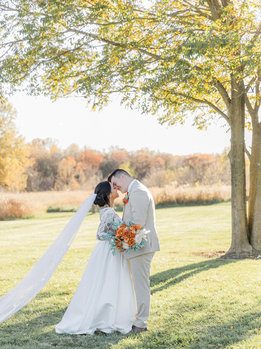 Bride and groom framed by autumn foliage at Cooper's Ridge Wedding Venue, captured by Love Tree Studios.