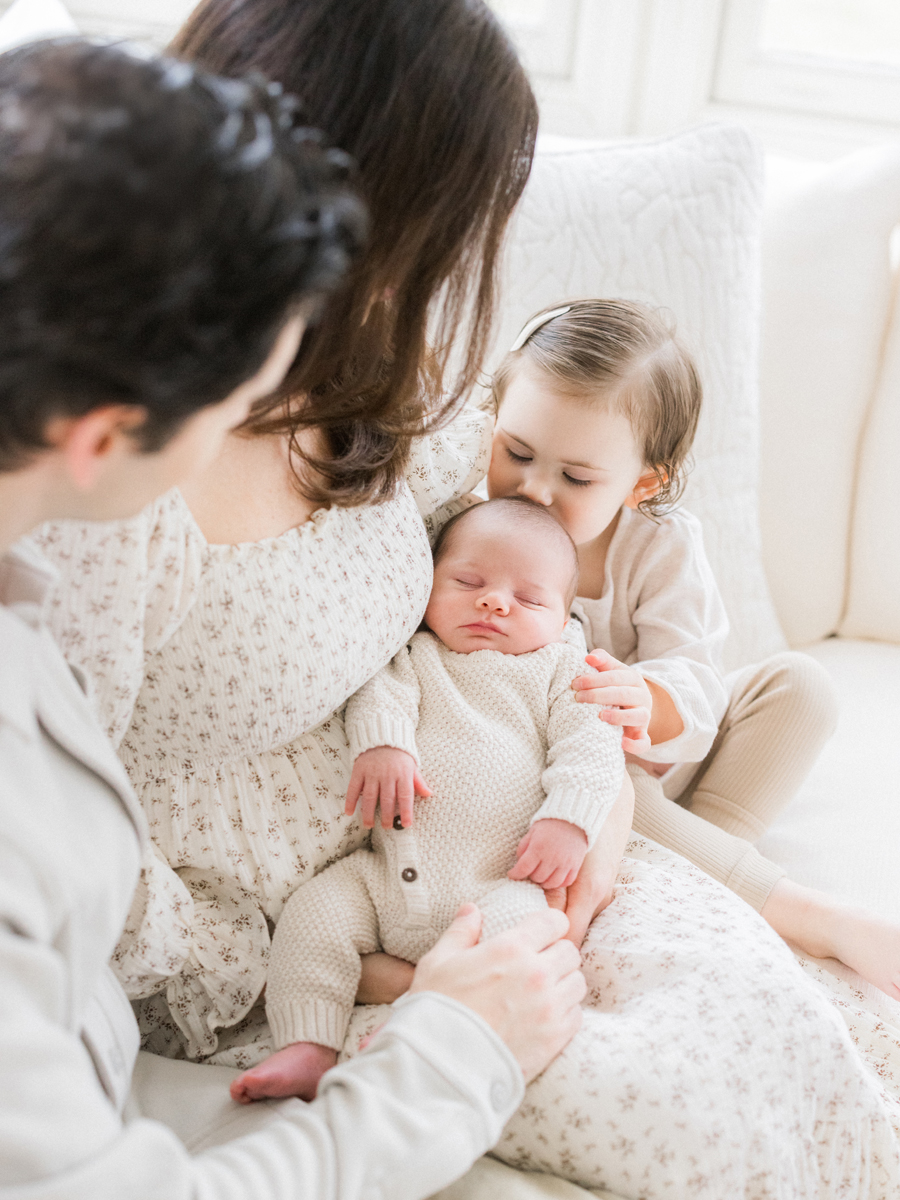 A heartwarming sibling moment with Millie kissing baby Harry, captured by Columbia Missouri Newborn Photographer - Love Tree Studios.