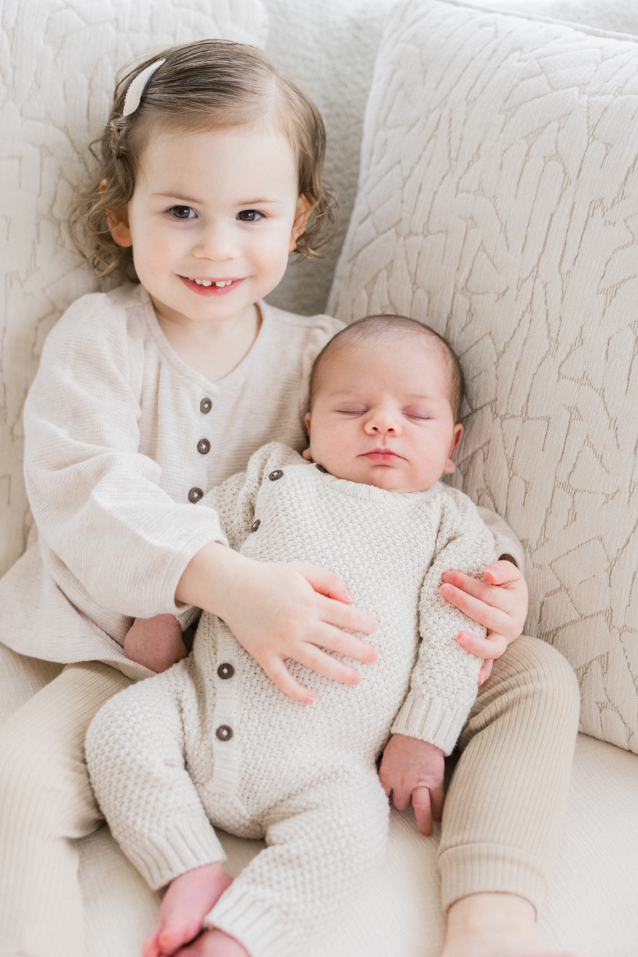 A proud big sister beaming with joy as she holds baby Harry in their Columbia Missouri Newborn Photography session - Love Tree Studios.