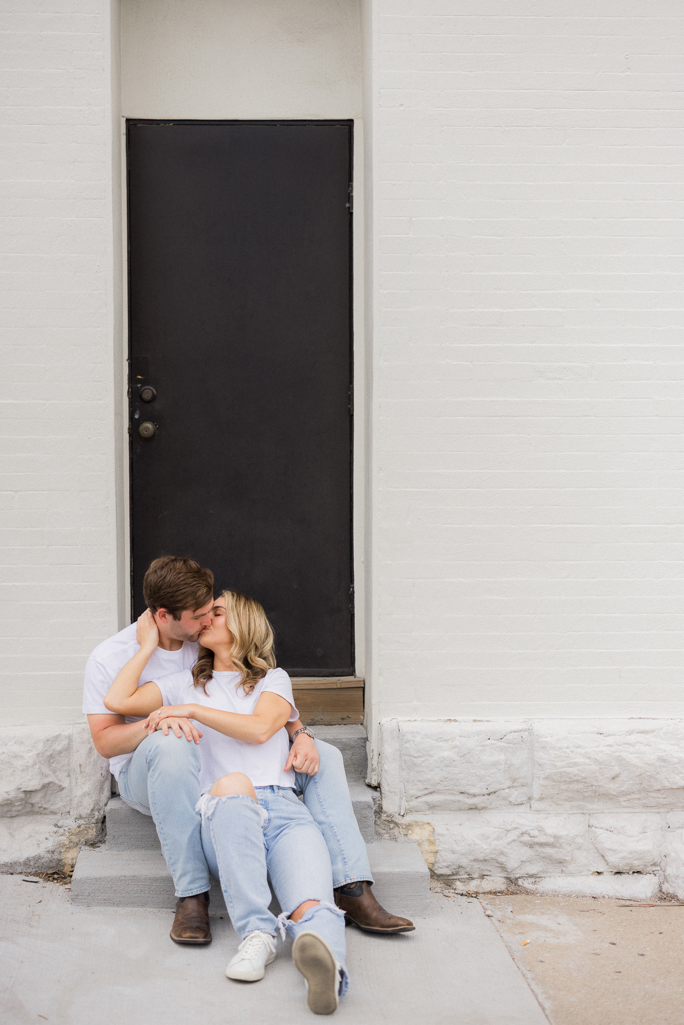 Sweet, candid moment of the couple leaning in for a kiss on a city street during their Missouri engagement photos.

