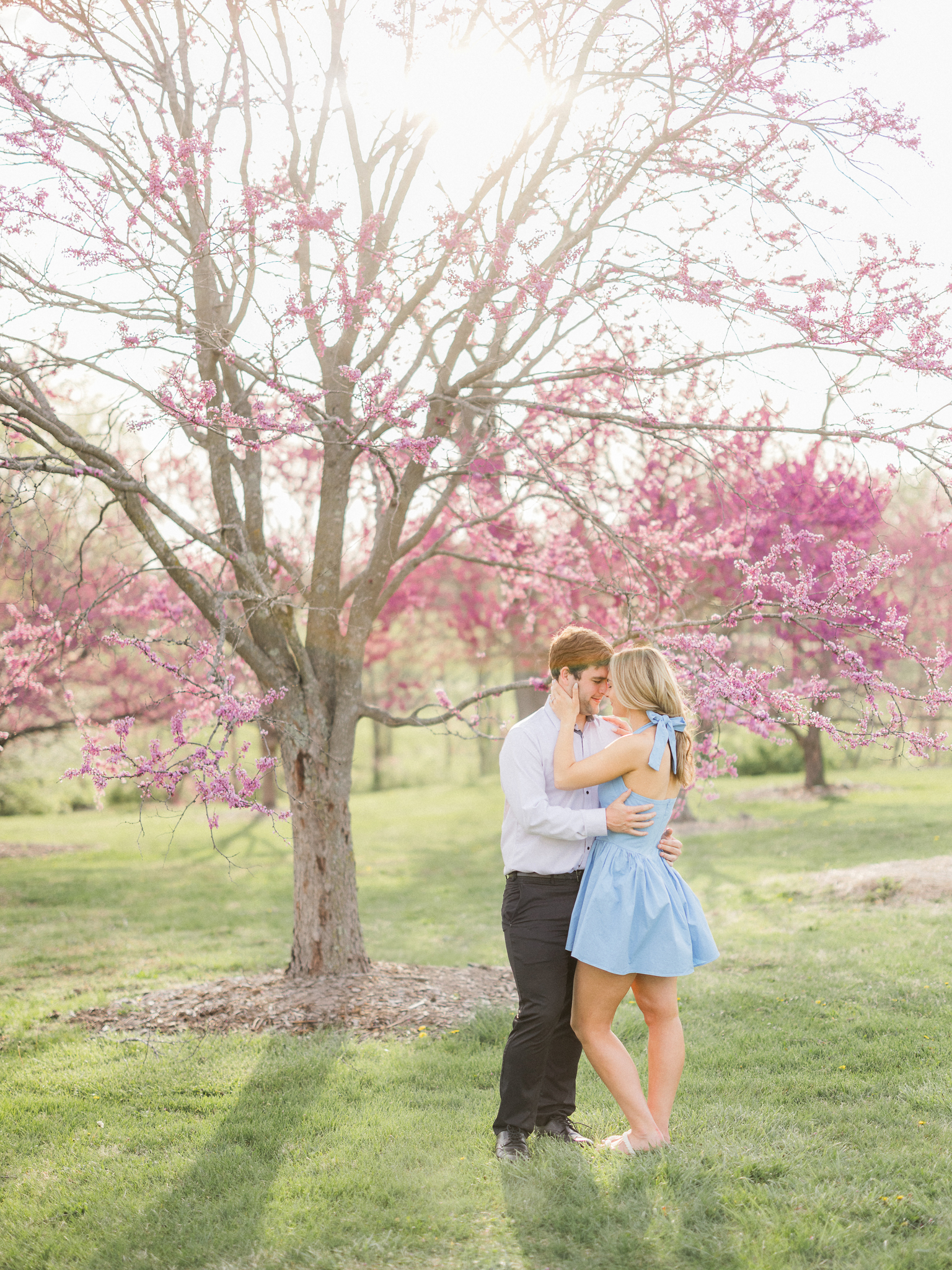 Couple embracing with joyful expressions during their spring engagement photos in a Missouri park.