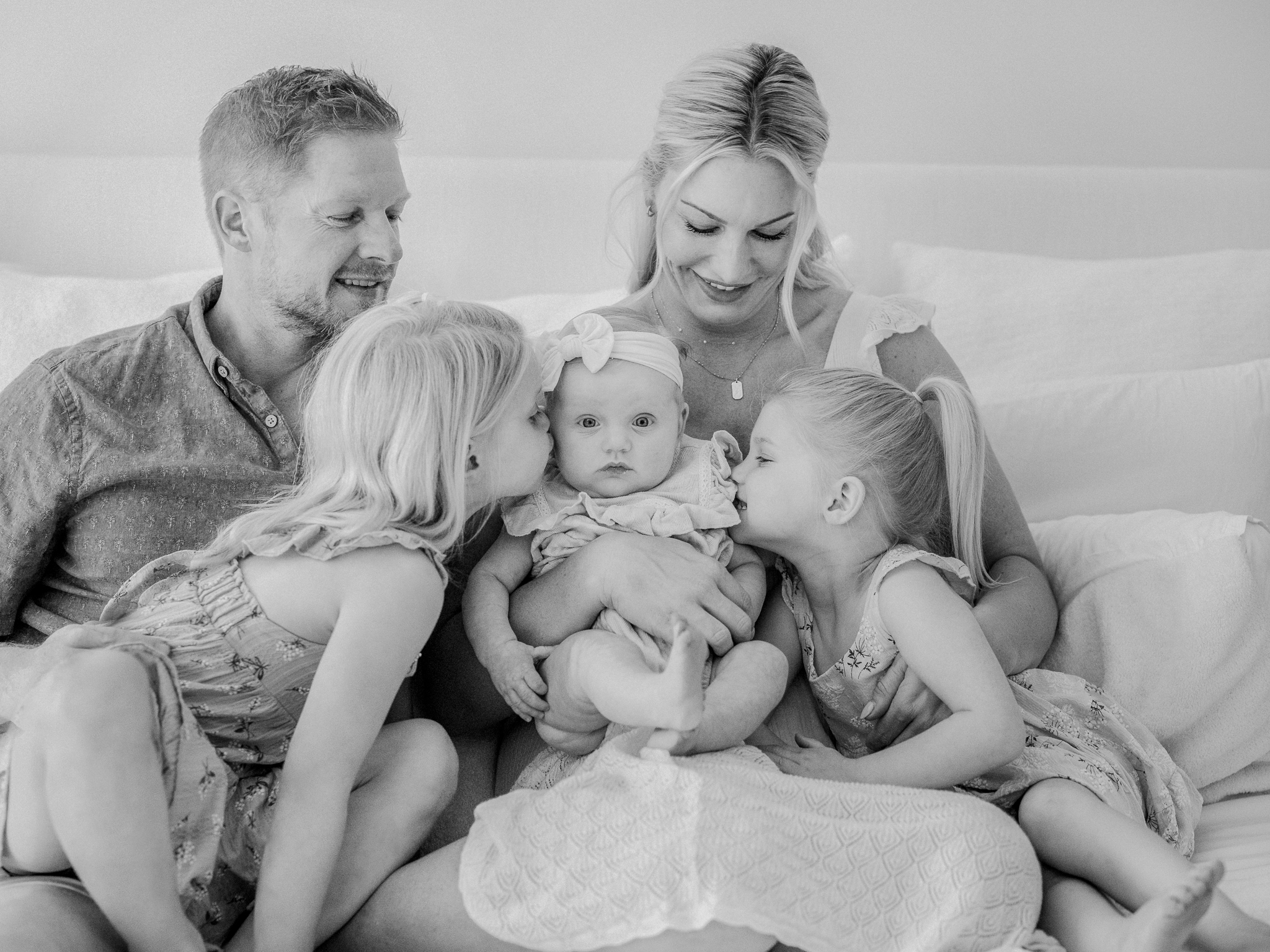 Family cuddled on the bed during an in-home newborn photography session in Missouri, captured by Love Tree Studios.